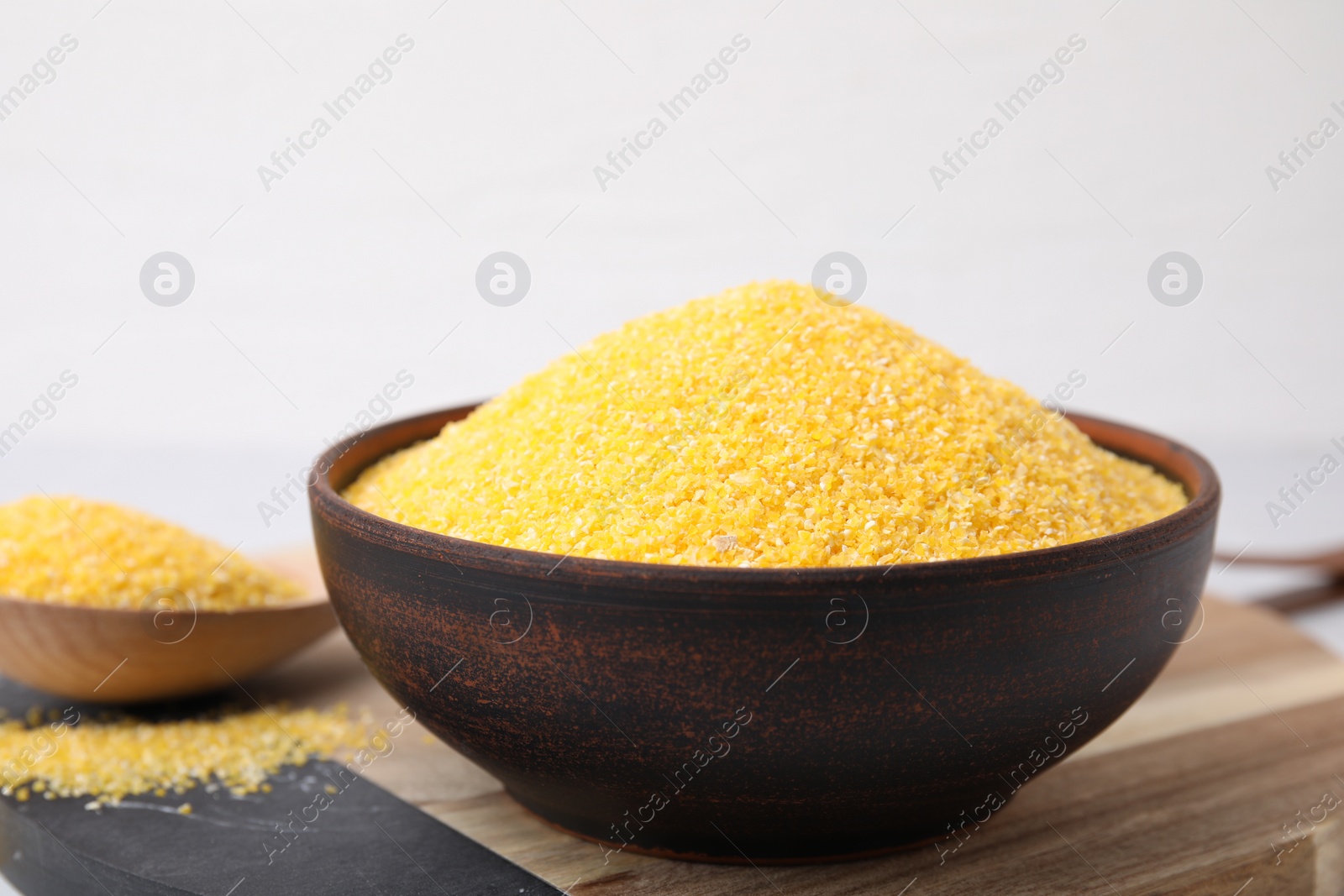 Photo of Raw cornmeal in bowl on table, closeup