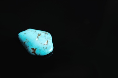 Beautiful turquoise gemstone on black background. Space for text