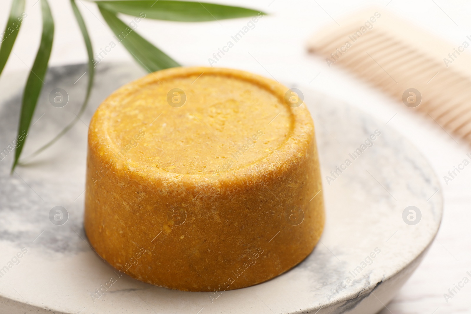 Photo of Dish with solid shampoo bar on table, closeup