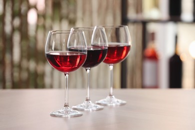 Photo of Different sorts of wine in glasses on table indoors