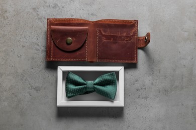 Photo of Stylish green bow tie and brown wallet on gray textured background, flat lay