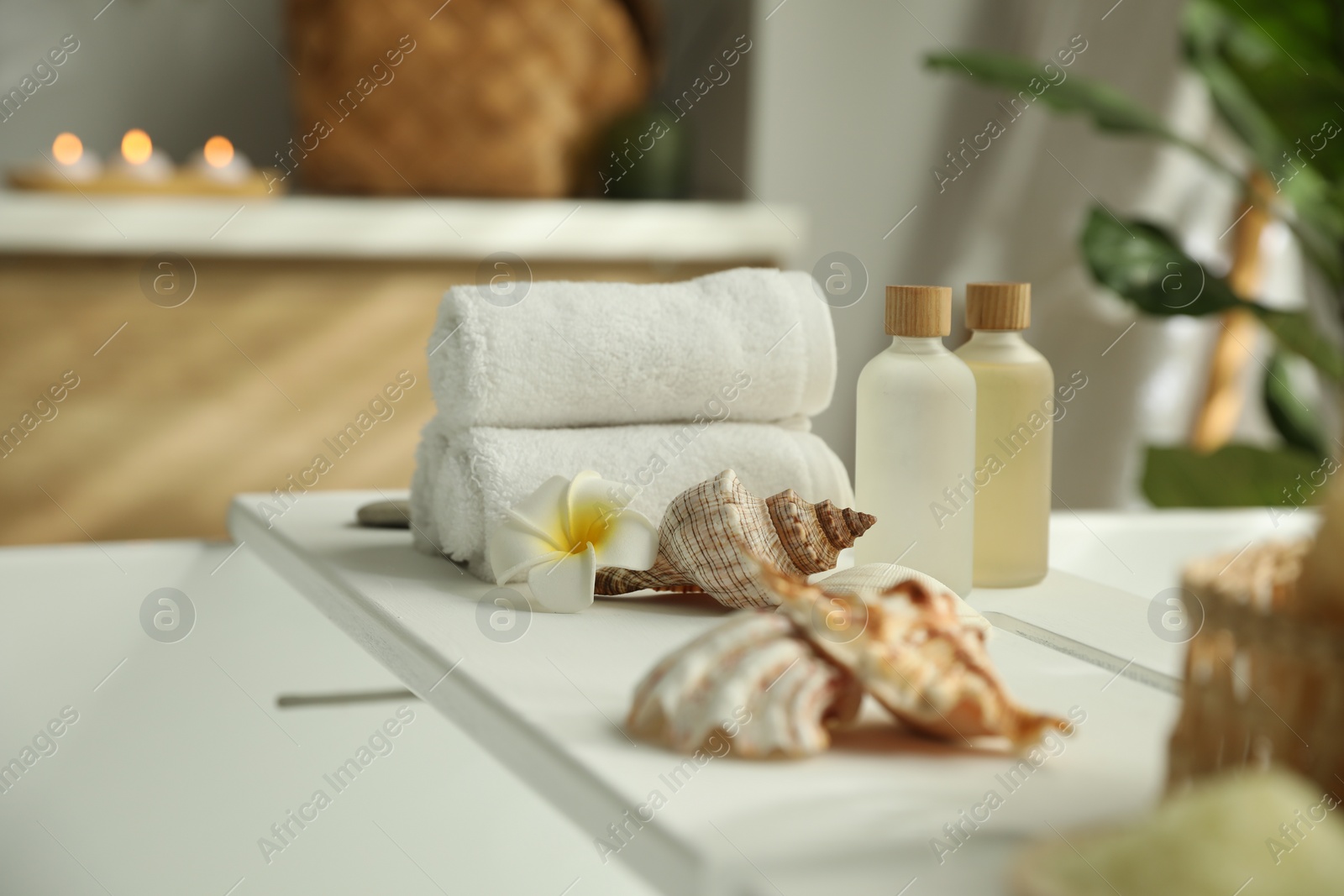 Photo of Bath tray with cosmetic products, towels and shells on tub in bathroom, space for text