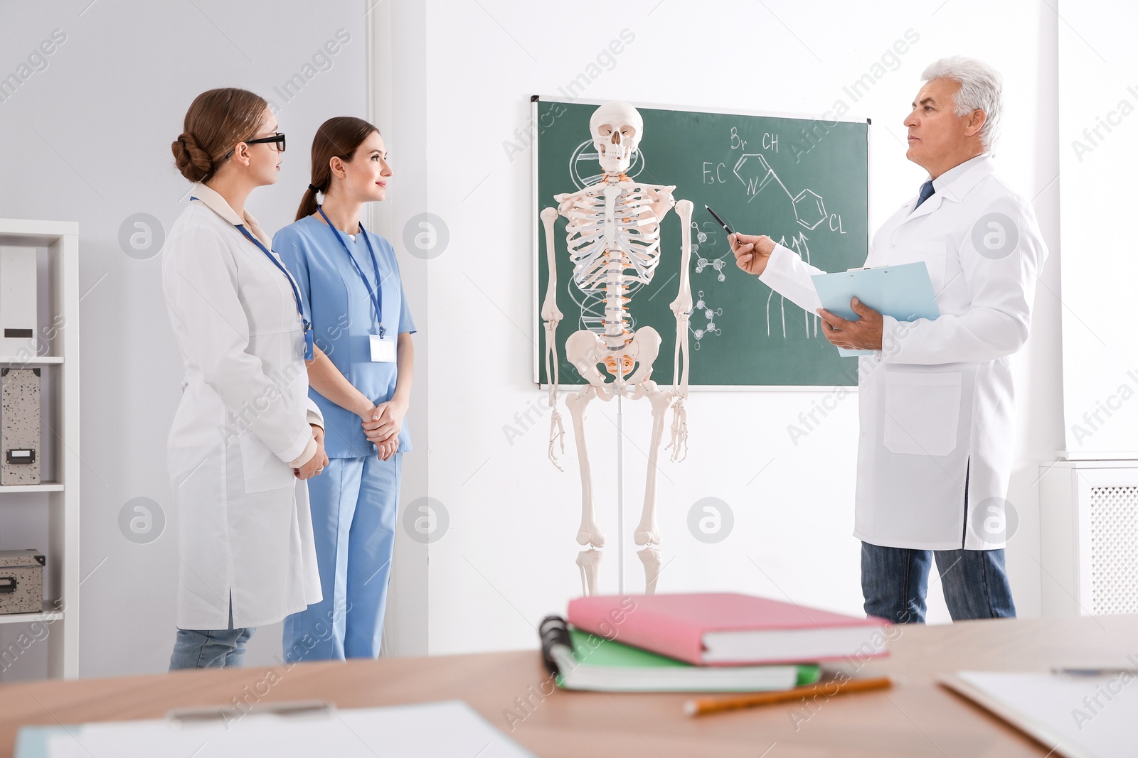 Photo of Medical students and professor studying human skeleton anatomy in classroom