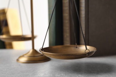 Photo of Scales of justice and books on table, closeup. Law concept