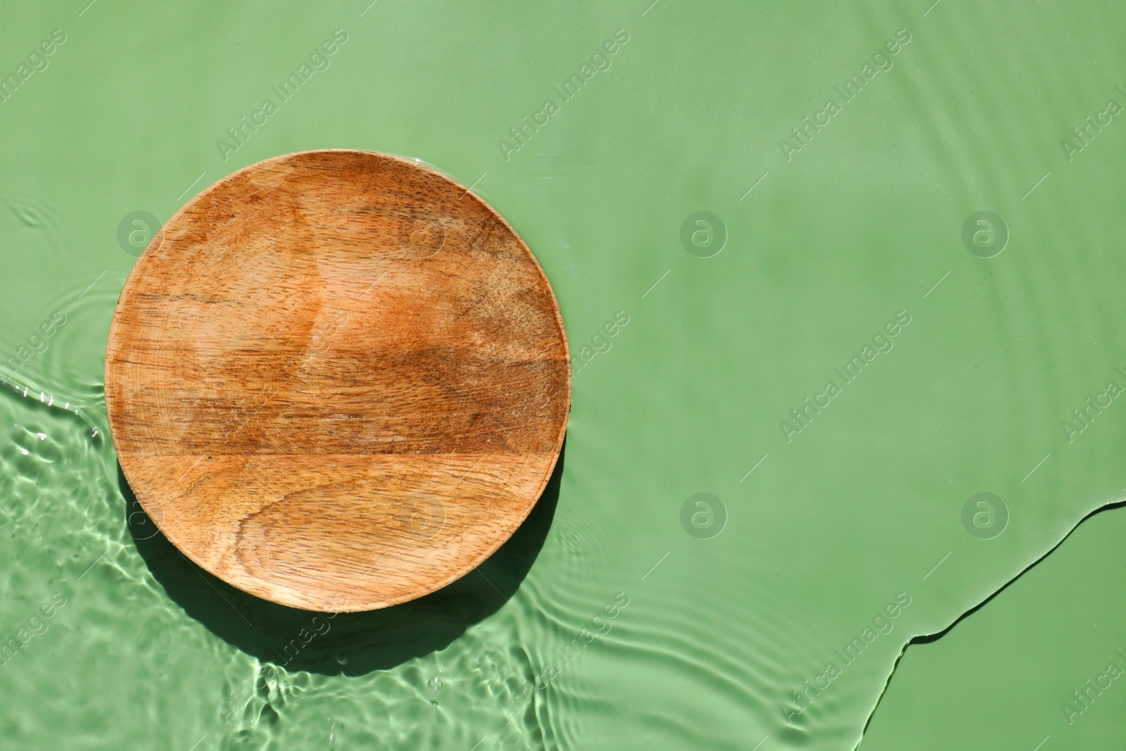 Photo of Presentation of product. Wooden podium in water on green background, top view. Space for text