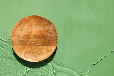 Photo of Presentation of product. Wooden podium in water on green background, top view. Space for text