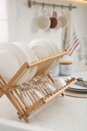 Photo of Drying rack with clean dishes on light marble countertop in kitchen