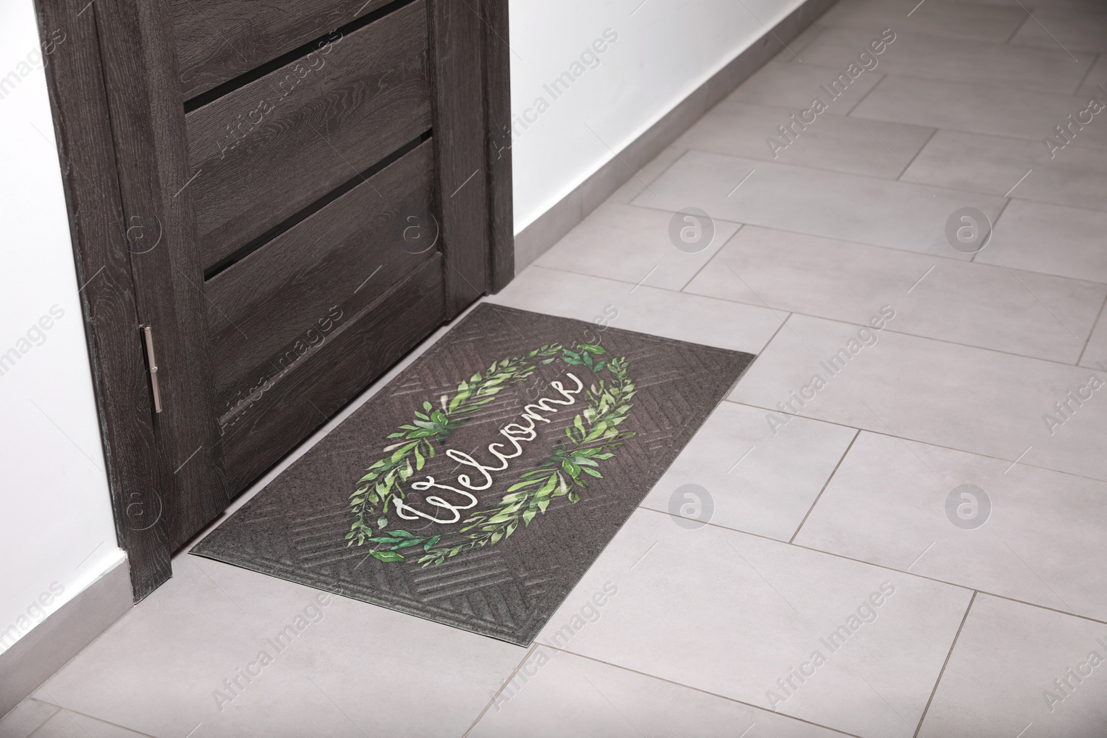 Photo of Beautiful doormat with word Welcome on floor near entrance