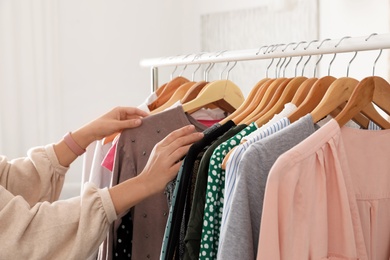 Photo of Woman choosing clothes from wardrobe rack, closeup