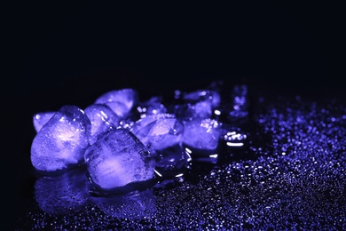 Photo of Melting ice cubes and water drops on black background. Space for text