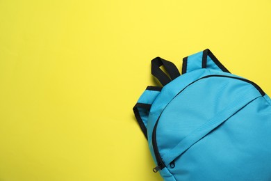 Stylish light blue backpack on yellow background, top view. Space for text