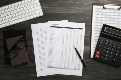 Photo of Accounting documents, glasses, stationery and computer keyboard on wooden table, flat lay