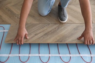 Photo of Professional contractor installing underfloor trace heating system indoors, closeup