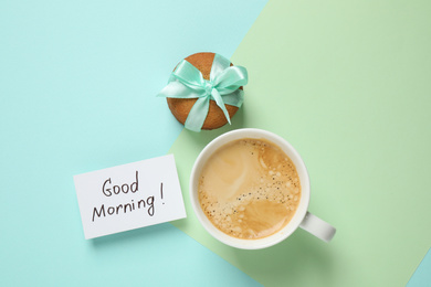 Photo of Message GOOD MORNING, cookie and coffee on color background, flat lay