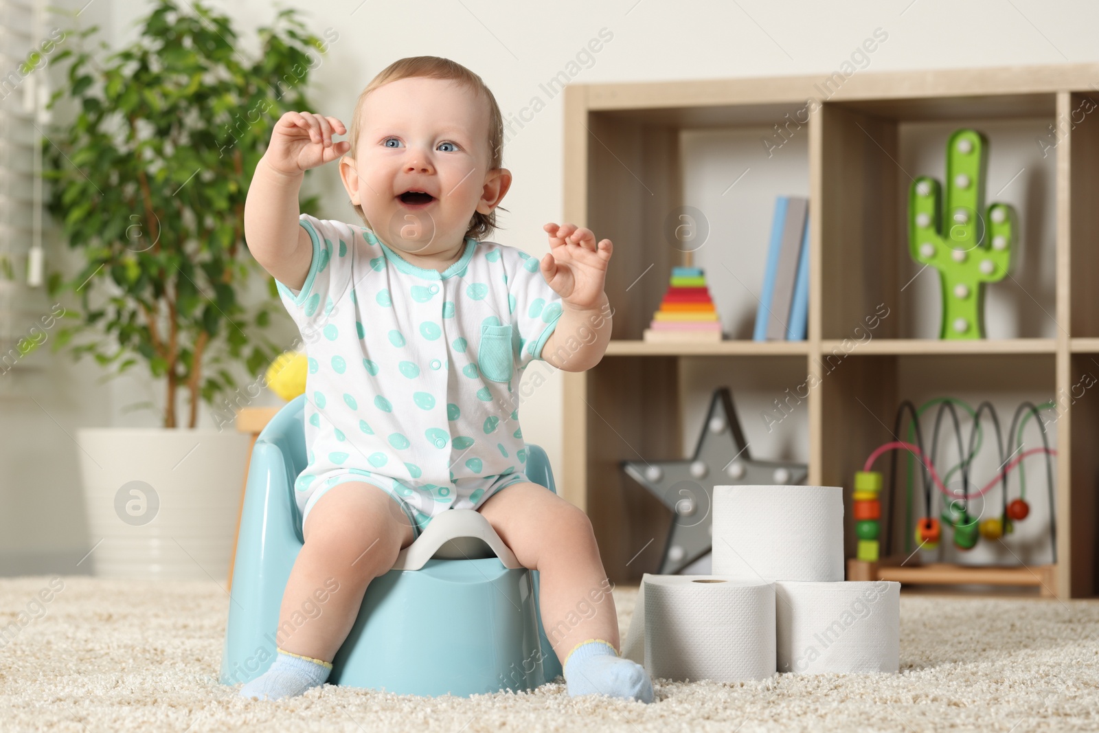 Photo of Little child sitting on plastic baby potty indoors. Space for text