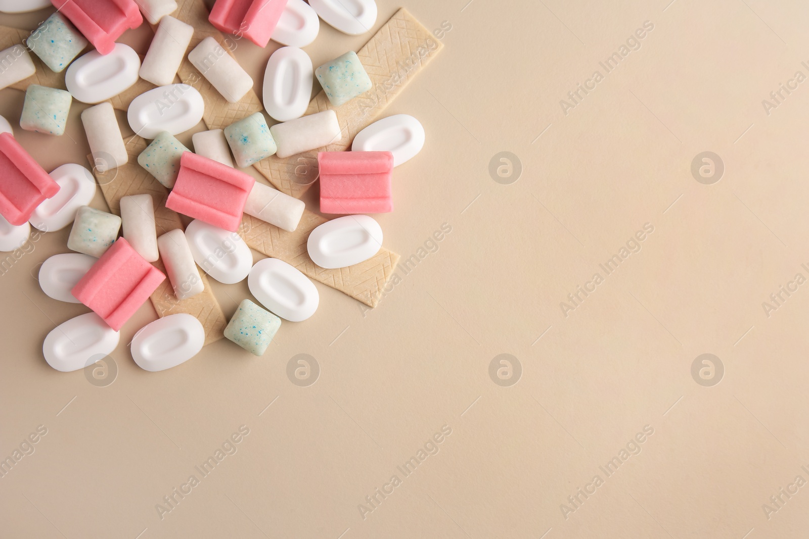 Photo of Many different chewing gums on beige background, flat lay. Space for text