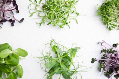Photo of Different microgreens on white background, top view
