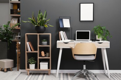 Workplace with laptop, stationery on desk and chair in home office