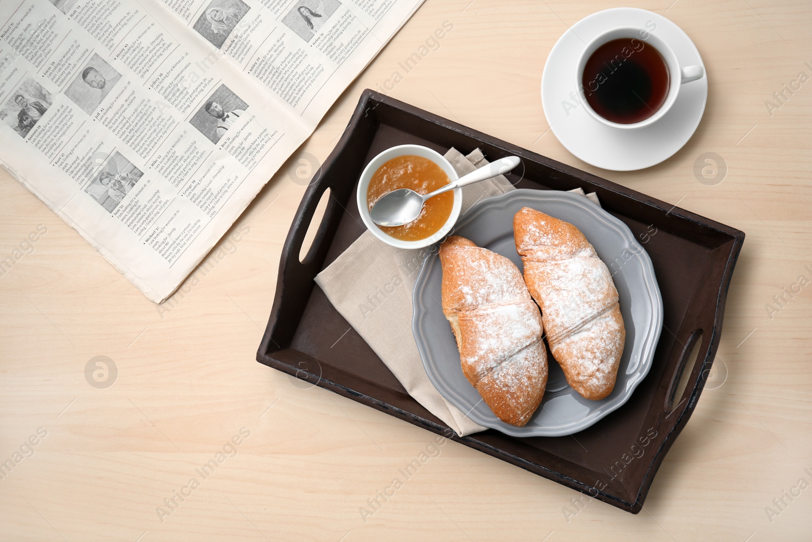 Photo of Tasty breakfast with fresh croissants, jam and cup of tea on table