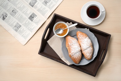 Tasty breakfast with fresh croissants, jam and cup of tea on table