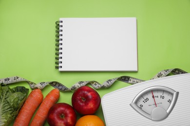 Photo of Notebook, scales, fresh fruits and vegetables on light green background, flat lay. Low glycemic index diet