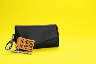 Photo of Leather case with key on yellow background. Space for text
