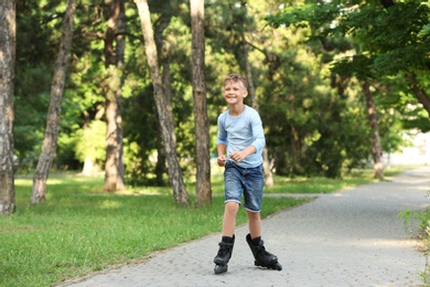 Photo of Little happy boy roller skating in park