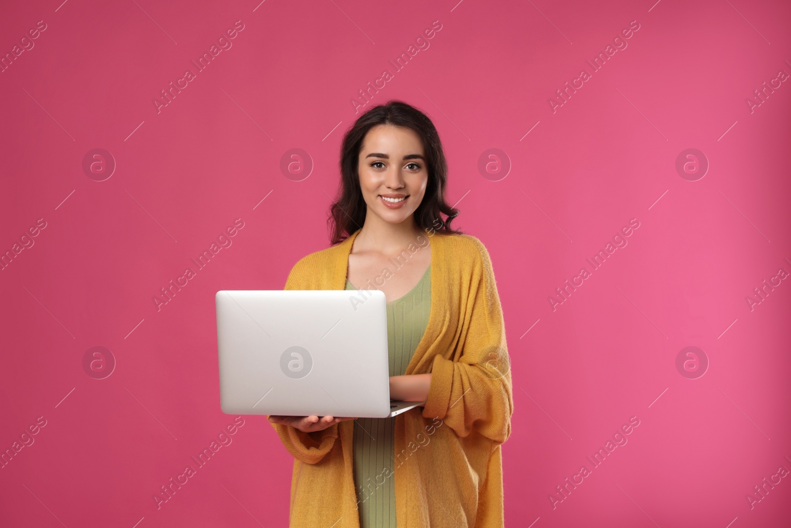 Photo of Young woman with laptop on pink background