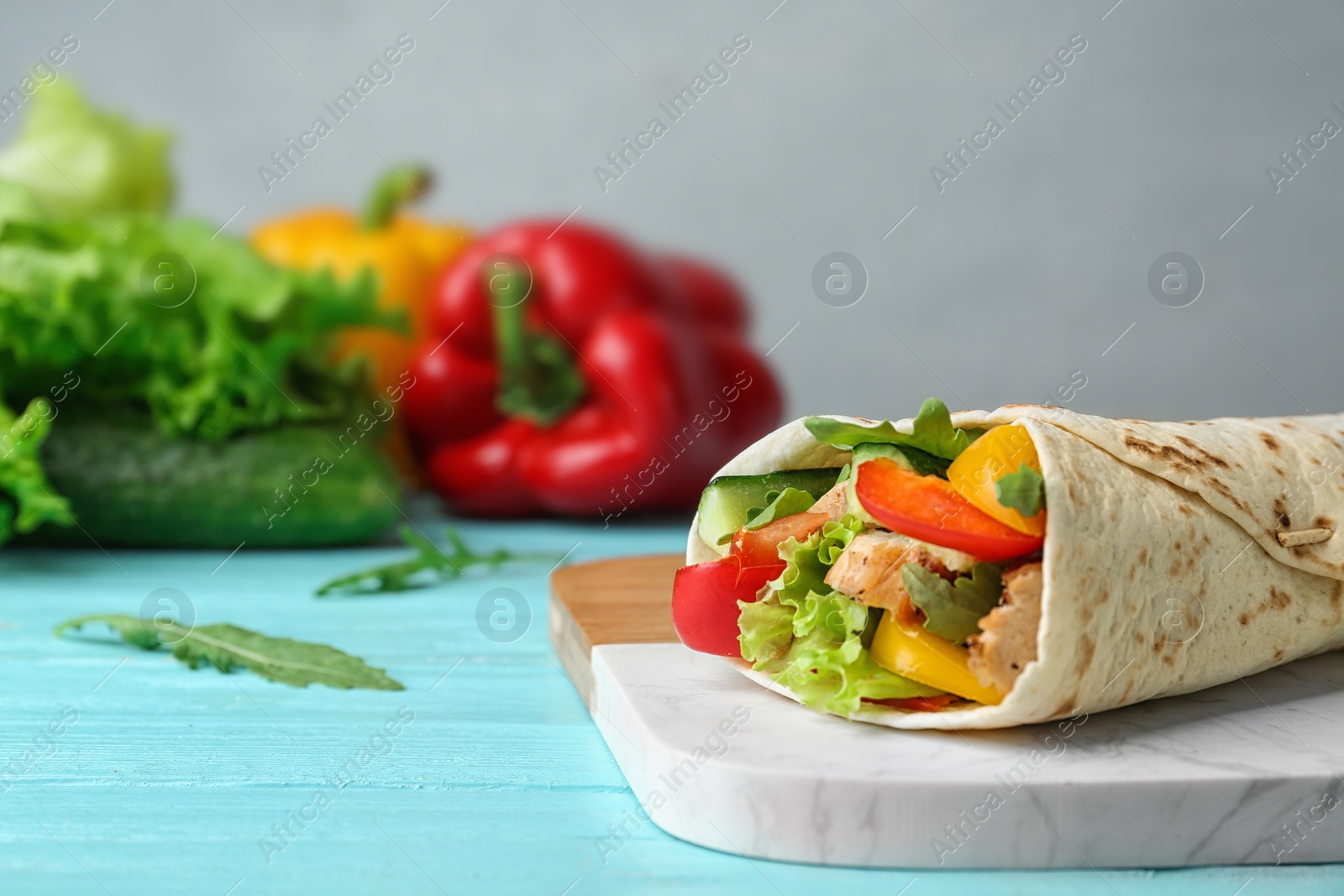 Photo of Delicious meat tortilla wrap on blue wooden table, space for text