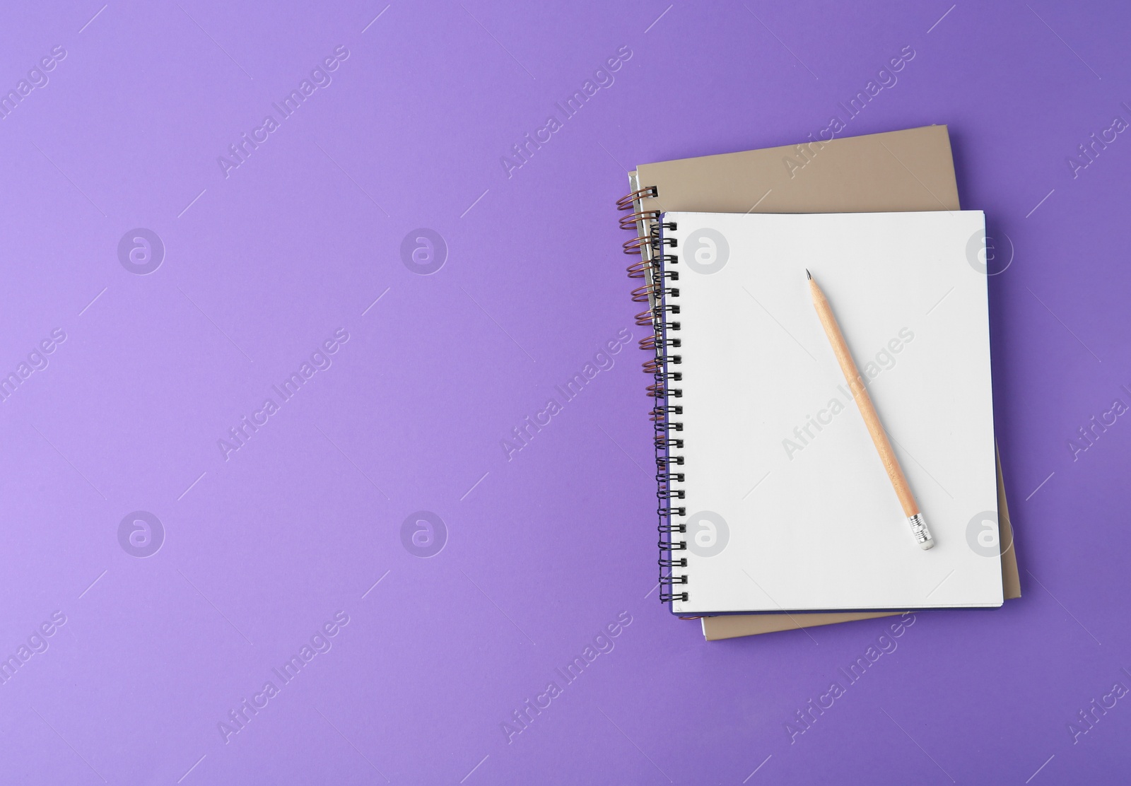 Photo of Notebooks with pencil on purple background, top view. Space for text