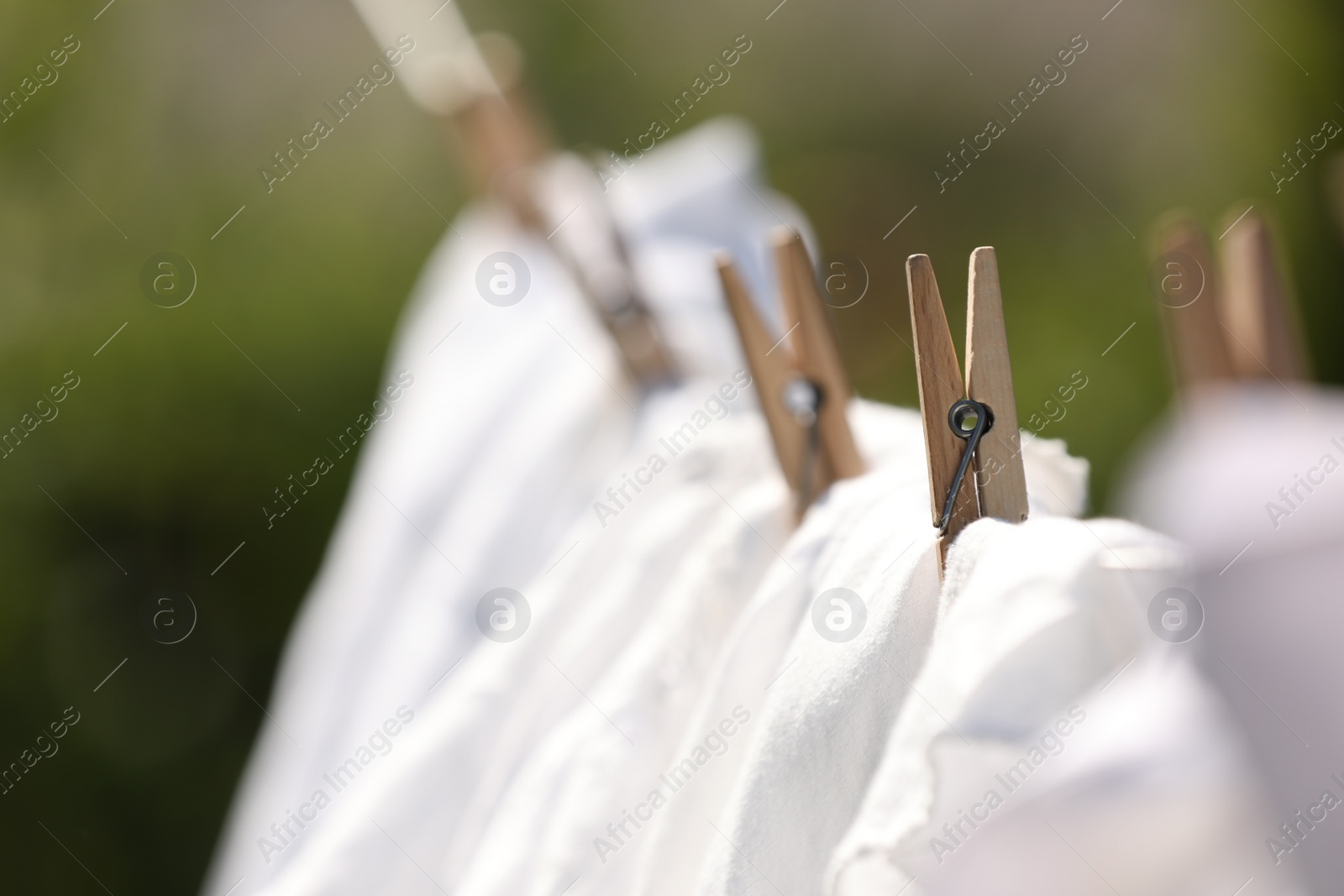 Photo of Clean clothes drying outdoors, closeup. Focus on clothespin