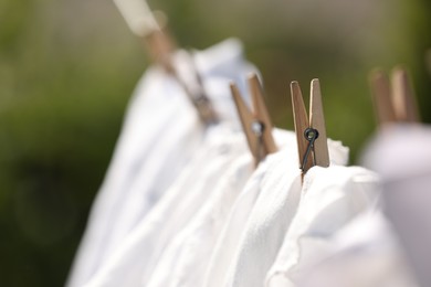 Clean clothes drying outdoors, closeup. Focus on clothespin