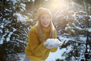 Woman holding snowballs outdoors on winter day