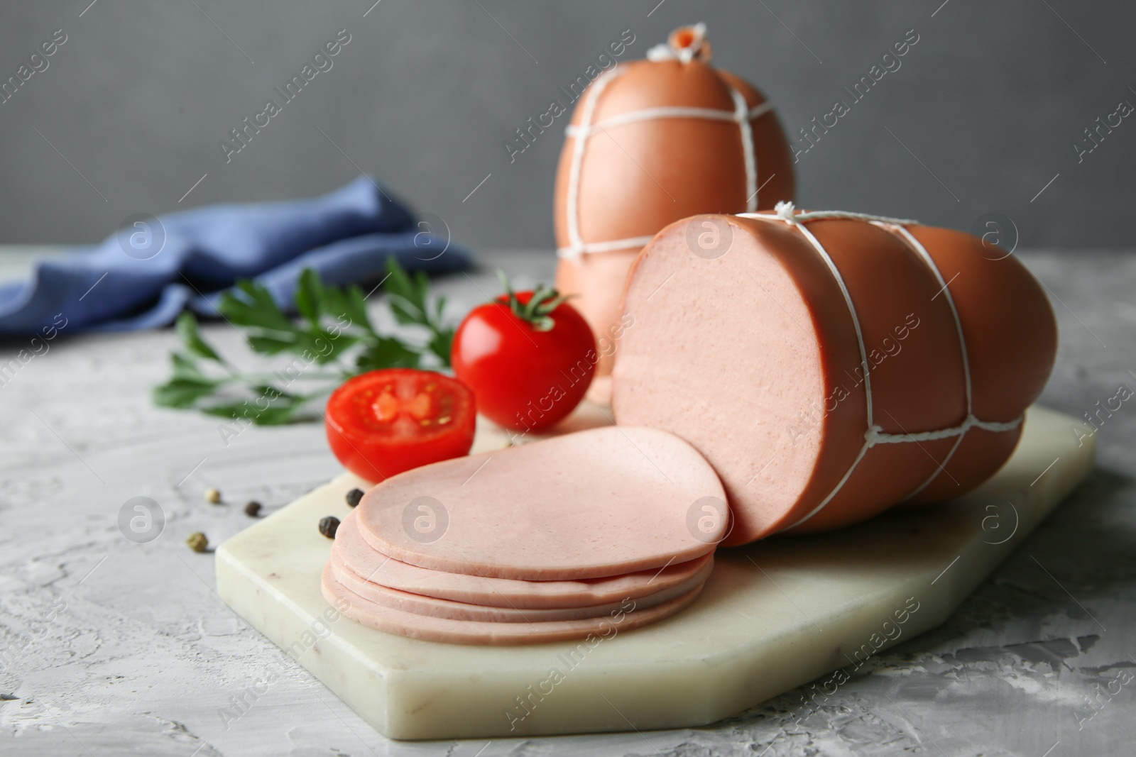 Photo of Delicious boiled sausage with tomatoes and spices on grey textured table