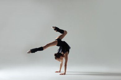 Photo of Cute little gymnast doing handstand on white background