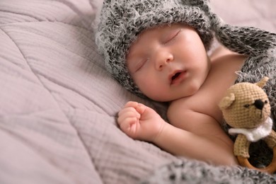 Photo of Cute newborn baby sleeping with teething toy in bed, closeup