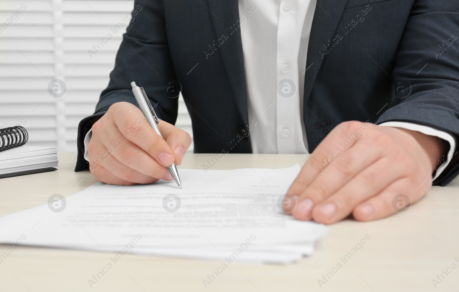 Photo of Man signing document at wooden table, closeup