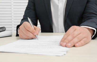 Man signing document at wooden table, closeup