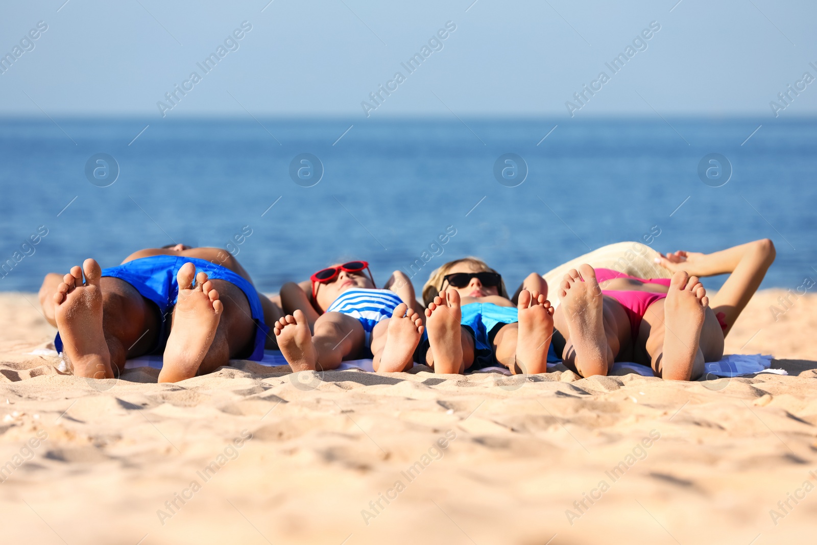 Photo of Family lying on sandy beach near sea. Summer holidays