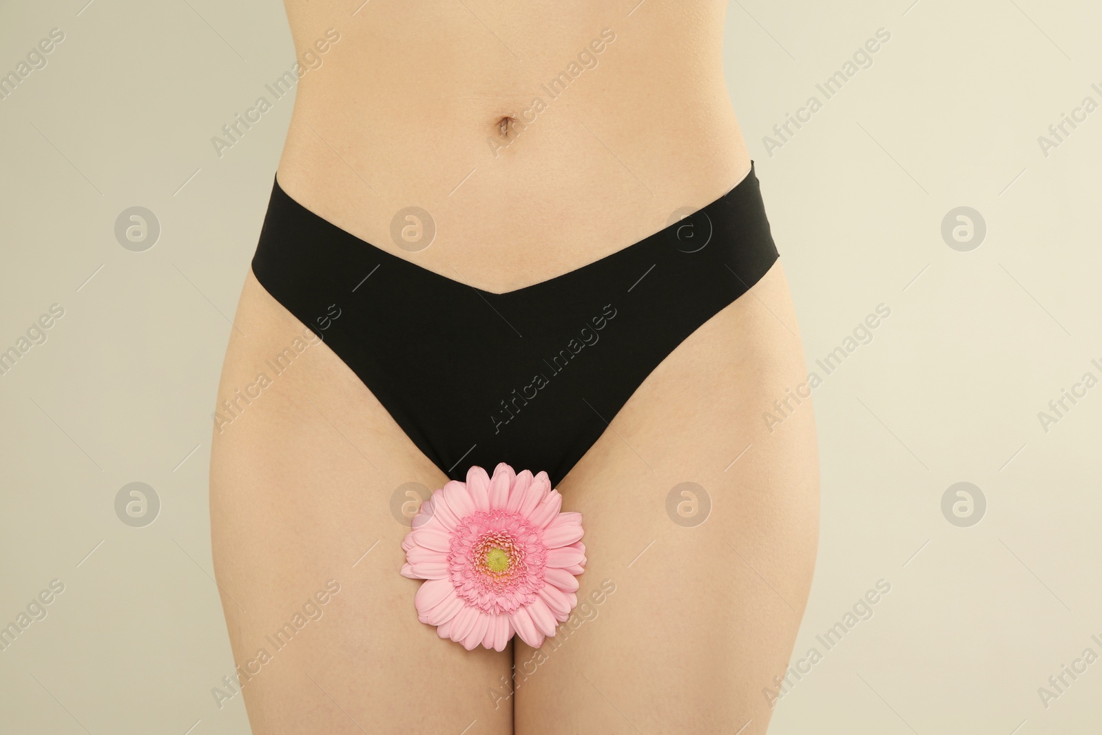 Photo of Gynecology. Woman in underwear with gerbera flower on light background, closeup