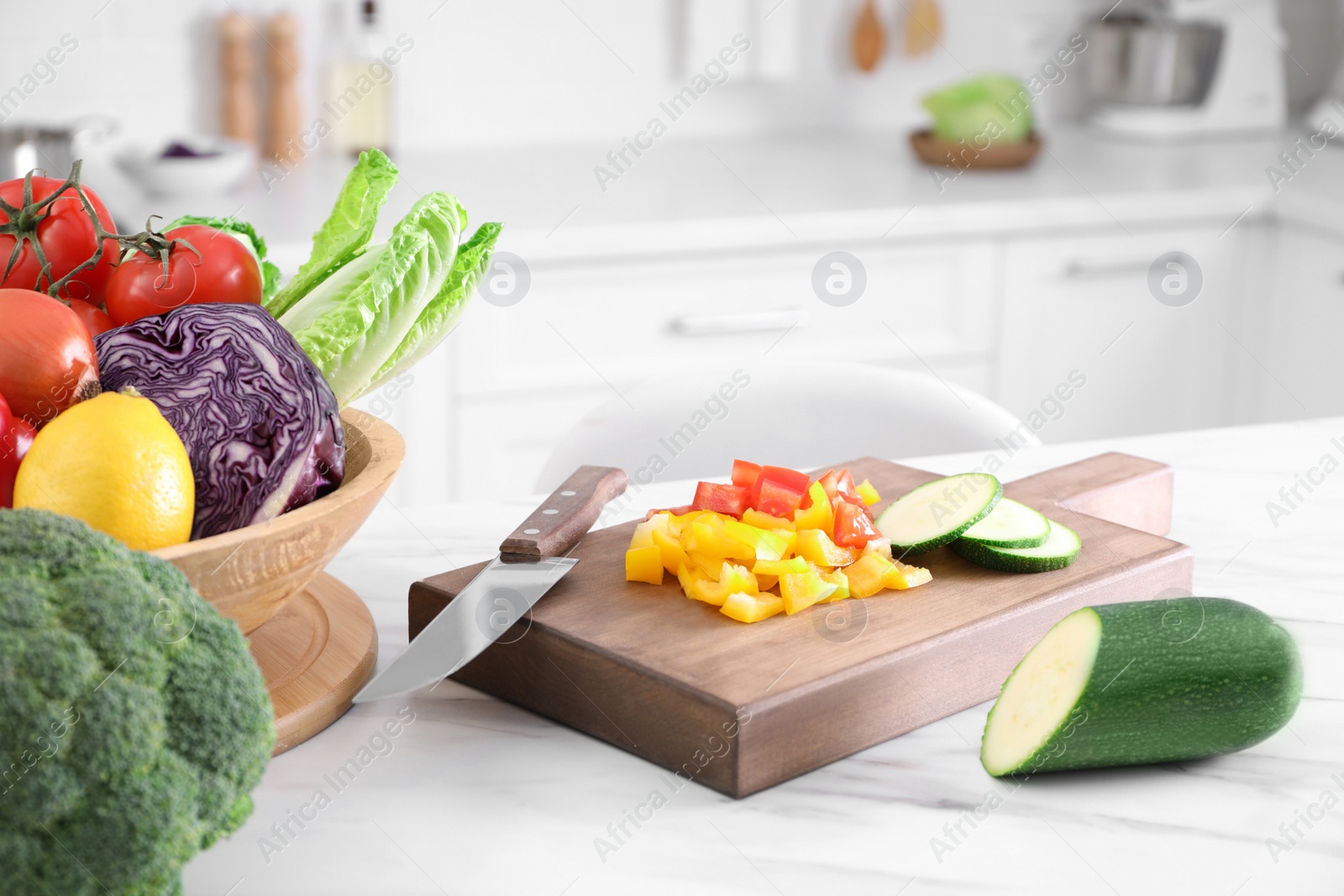 Photo of Different raw vegetables on white marble table in kitchen