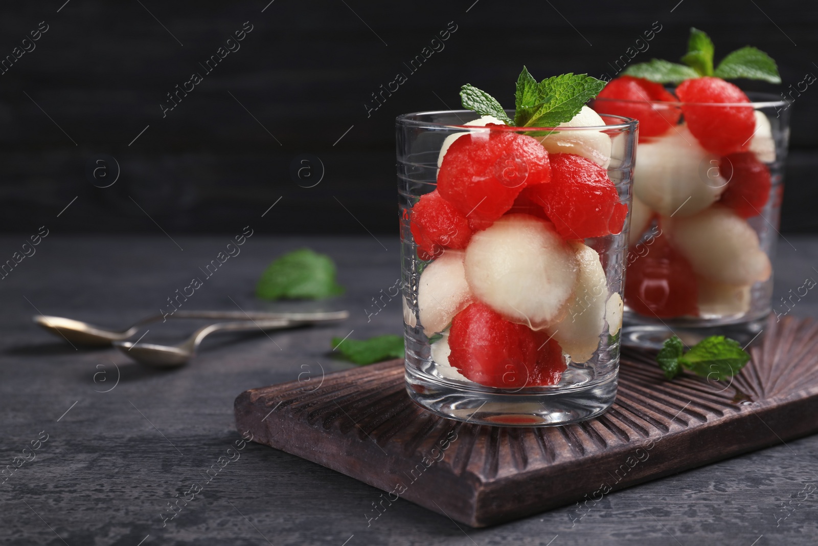 Photo of Glasses with melon and watermelon balls on table. Space for text