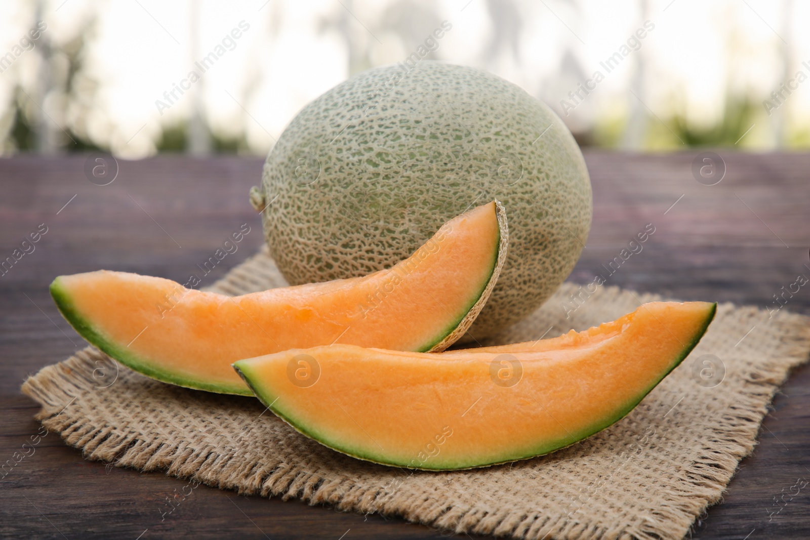 Photo of Cut and whole delicious ripe melons on wooden table outdoors