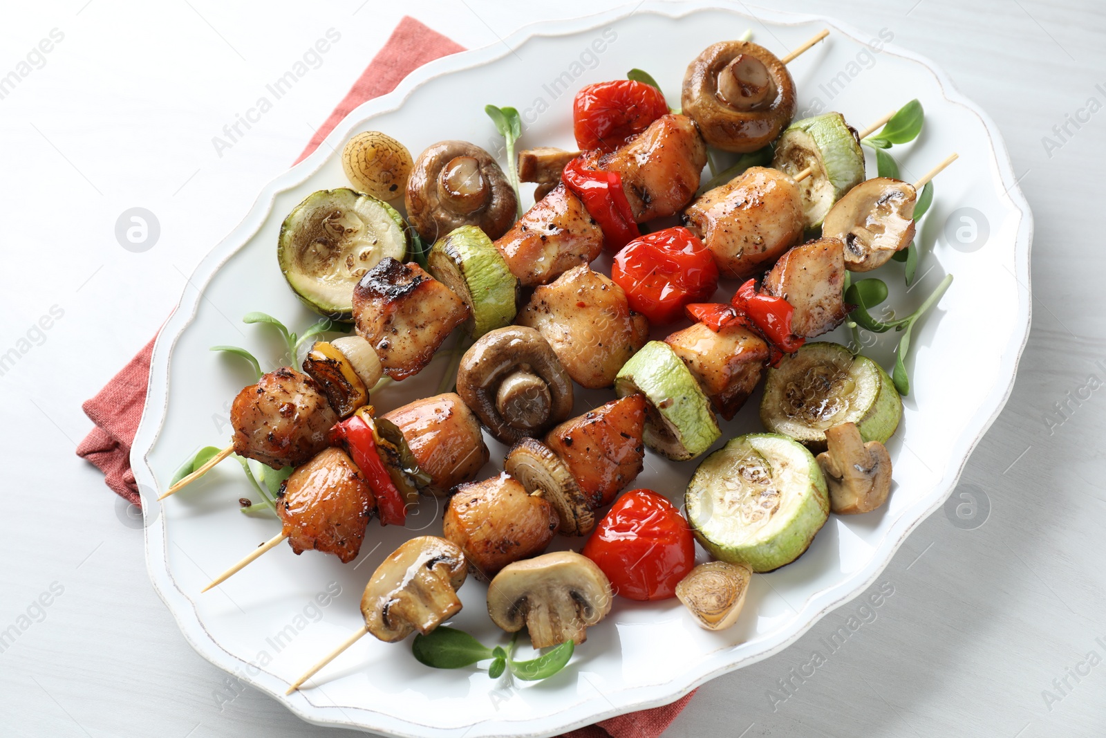Photo of Delicious shish kebabs with vegetables and microgreens on white table, top view