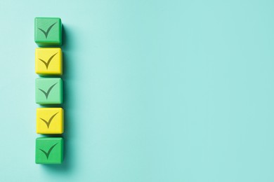 Image of Cubes with check marks on turquoise background, top view. Space for text