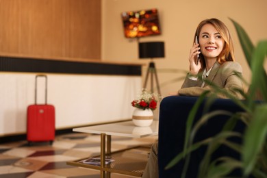 Beautiful woman talking on phone while waiting in hotel hall