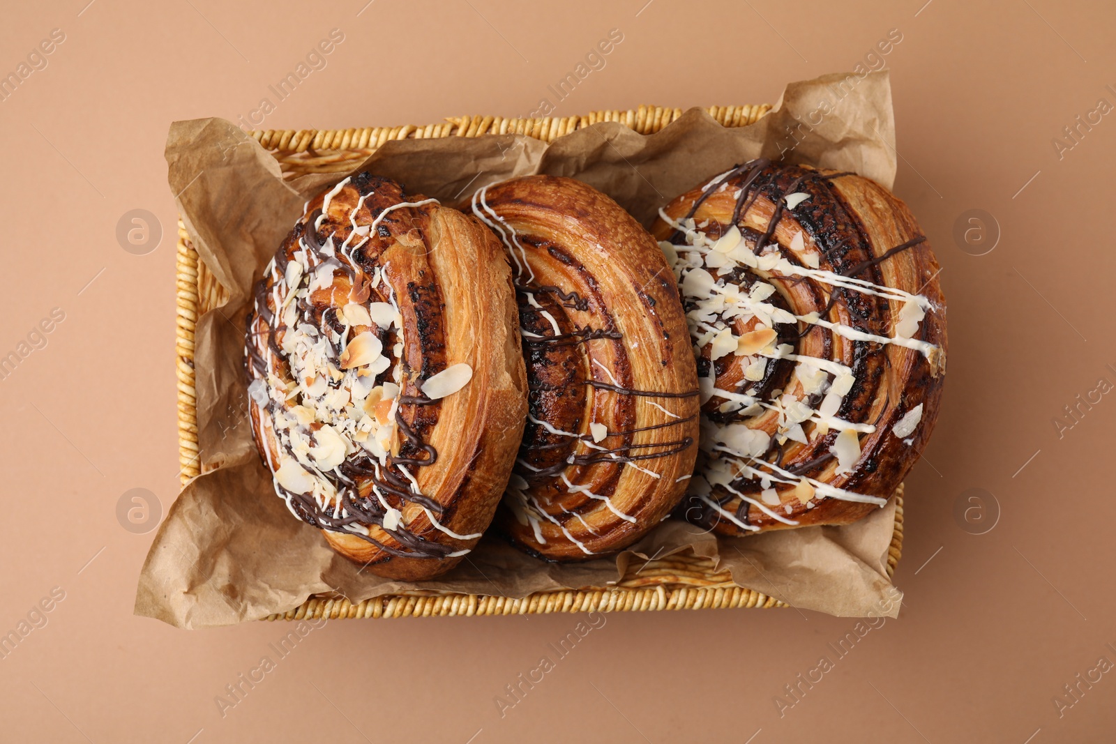 Photo of Delicious rolls with toppings and almond on beige table, top view. Sweet buns