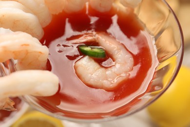 Photo of Tasty shrimp cocktail with sauce in glass on table, closeup