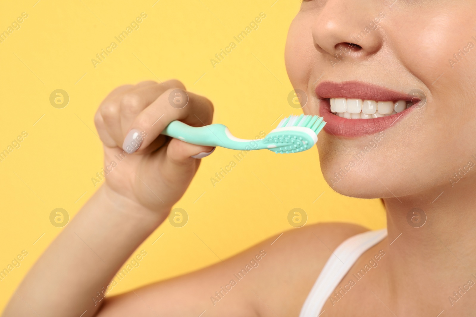 Photo of Beautiful woman brushing teeth on color background, closeup