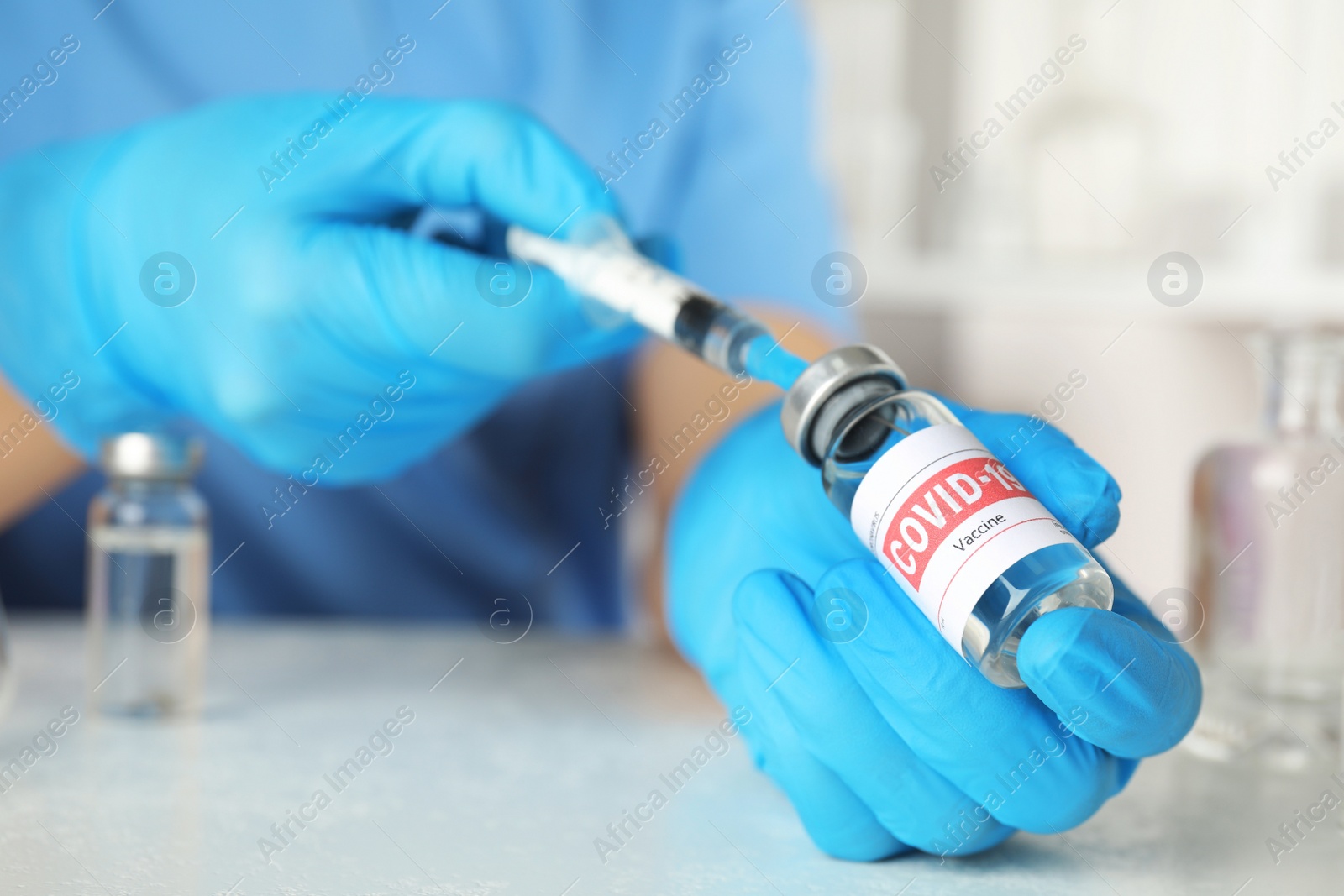 Photo of Doctor filling syringe with coronavirus vaccine at table in laboratory, closeup